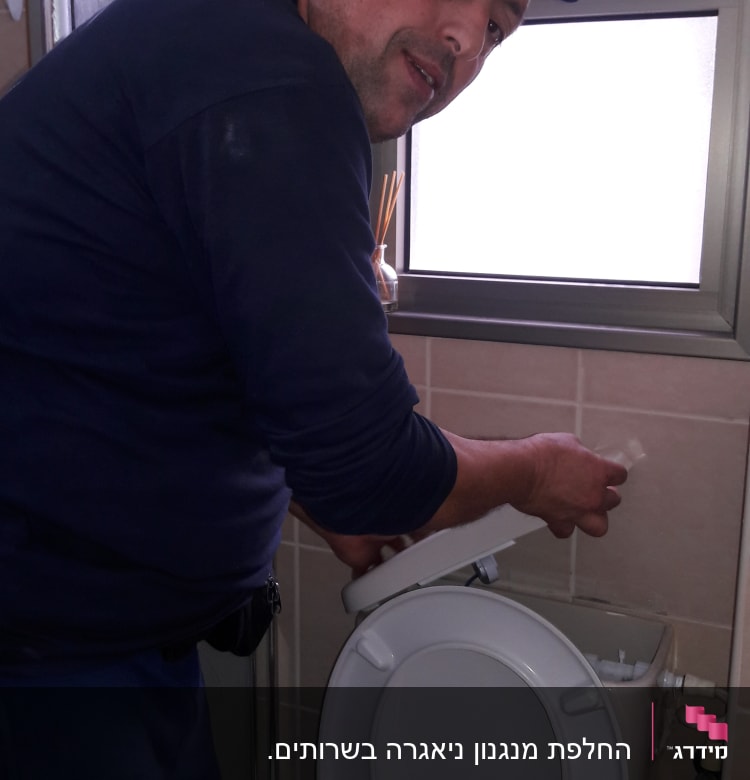 אדם מתקן אסלה בחדר אמבטיה